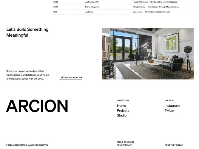 Modern living room with black-framed glass doors, white walls, tufted sofa, black leather chairs, and framed artwork.